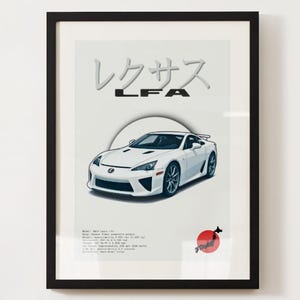 May include: Framed print featuring a white Lexus LFA sports car illustration. The artwork includes Japanese characters and the text "LFA" in a bold font. A red circle with a black silhouette is in the lower right corner. The print is in a black frame.