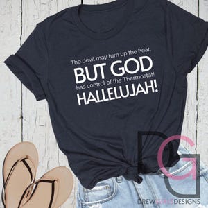 May include: A navy blue t-shirt with white text that reads "The devil may turn up the heat, BUT GOD has control of the Thermostat! HALLELUJAH!"