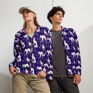 May include: A purple zip-up jacket featuring a white dog pattern. The jacket has a collared neckline and a full-length zipper. The dog pattern is repeated across the jacket's surface. The jacket is worn by a person.