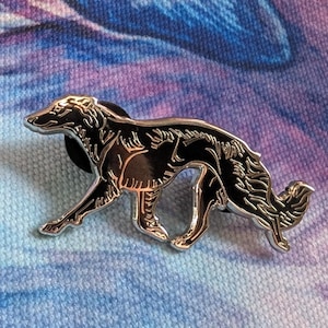 K&ouml;nnte beinhalten: Ein silberfarbener Metall-Pin in Form eines Borzoi-Hundes. Der Pin hat eine schwarze Emaille-F&uuml;llung und ist vor einem blau-violetten Hintergrund platziert. Der Hund wird in einer Laufpose mit detaillierten Merkmalen dargestellt.