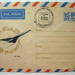 Pode incluir: Um envelope vintage com uma borda listrada vermelha, branca e azul. O envelope tem um selo com o retrato de uma pessoa e a palavra "MIR" em azul. O envelope também tem um selo circular com o texto "ПОЛТАВА * ВЕЛИКО-ТЫРНОВО ВЫСТАВКА" em preto. O envelope tem o texto "PAR AVION" em azul e o texto "Ту-144" em preto. O envelope tem um desenho de um avião supersônico.