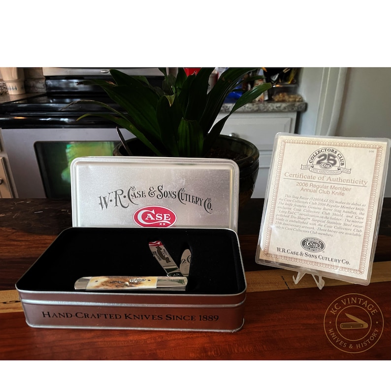 Puede incluir: Una navaja de bolsillo vintage con mango de hueso, exhibida en una caja met&aacute;lica. La caja est&aacute; marcada con "W.R. Case & Sons Cutlery Co." y "Hand Crafted Knives Since 1889." Tambi&eacute;n hay un certificado de autenticidad.