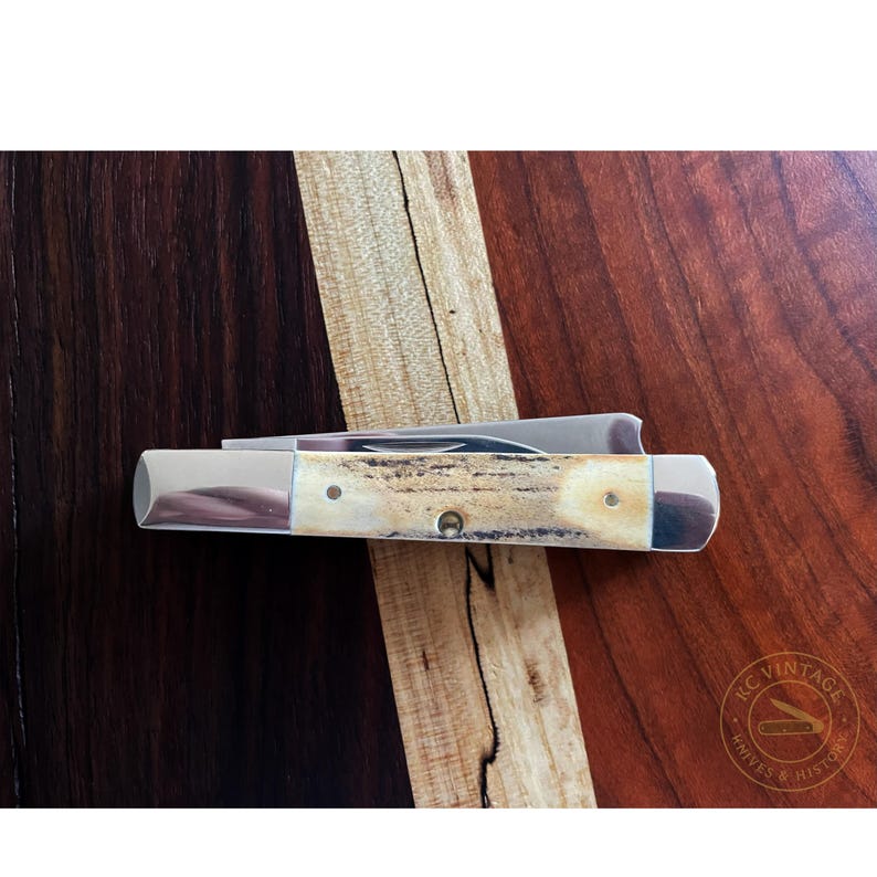 Puede incluir: Una navaja de bolsillo cerrada con una hoja y un mango de metal pulido. El mango tiene un patr&oacute;n marr&oacute;n claro y crema. El cuchillo est&aacute; sobre una superficie de madera oscura con detalles de madera m&aacute;s claros. Es un art&iacute;culo vintage.