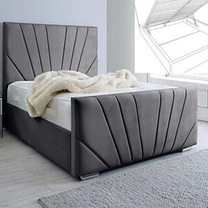May include: A grey upholstered bed with a headboard and footboard featuring a fan design. The bed has a mattress and a cream blanket. The bed frame is dark grey. A small bedside table with a mirror is visible. The bed is suitable for a double or king size mattress.