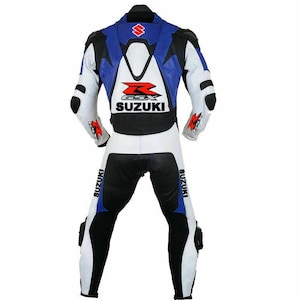 May include: A white, blue, and black Suzuki motorcycle racing suit. The suit features the Suzuki logo on the back and legs, with black accents on the shoulders, elbows, and knees. The suit is designed for protection and speed.