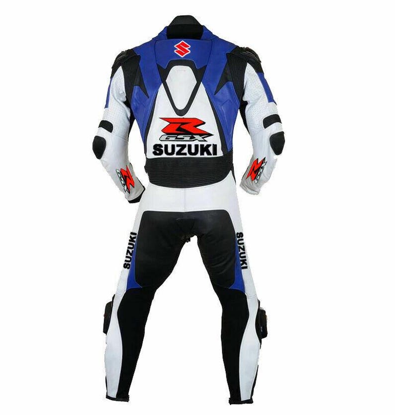 May include: A white, blue, and black Suzuki motorcycle racing suit. The suit features the Suzuki logo on the back and legs, with black accents on the shoulders, elbows, and knees. The suit is designed for protection and speed.