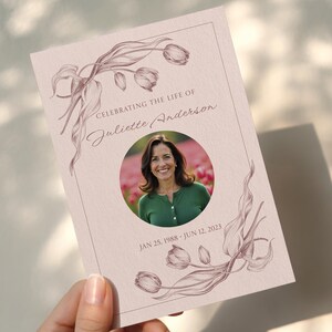 Peut inclure: Carte de deuil avec une photo d'une femme en pull vert, entourée d'une bordure florale rose. Le texte indique "Célébrer la vie de Juliette Anderson" et inclut ses dates de naissance et de décès.
