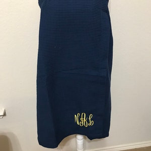 May include: A navy blue waffle weave bath wrap with a yellow embroidered monogram "N&L".