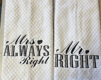 May include: Two white waffle-weave kitchen towels featuring black embroidered text. The left towel reads Mrs. ALWAYS Right with a small heart, and the right towel reads Mr. RIGHT with a small heart. The fabric has a textured, grid-like pattern.