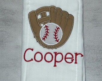 May include: A white rectangular fabric towel featuring an embroidered brown baseball glove holding a white baseball with red stitching. Below the baseball graphic, the name Cooper is embroidered in red thread using a cursive script font.