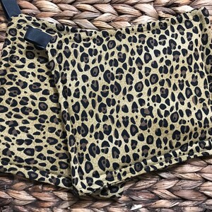 May include: Two brown and black leopard print pot holders with a black strap on one of them.