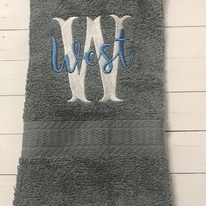 May include: A gray hand towel with the word "West" embroidered in white with blue accents.