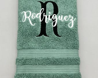 May include: A green hand towel with a white embroidered name "Rodriguez" and a black embroidered initial "R".