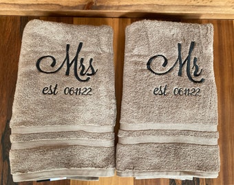 Peut inclure: Deux serviettes de toilette brunes avec du texte brodé. La serviette de gauche dit "Mrs. est 061122" et la serviette de droite dit "Mr. est 061122".