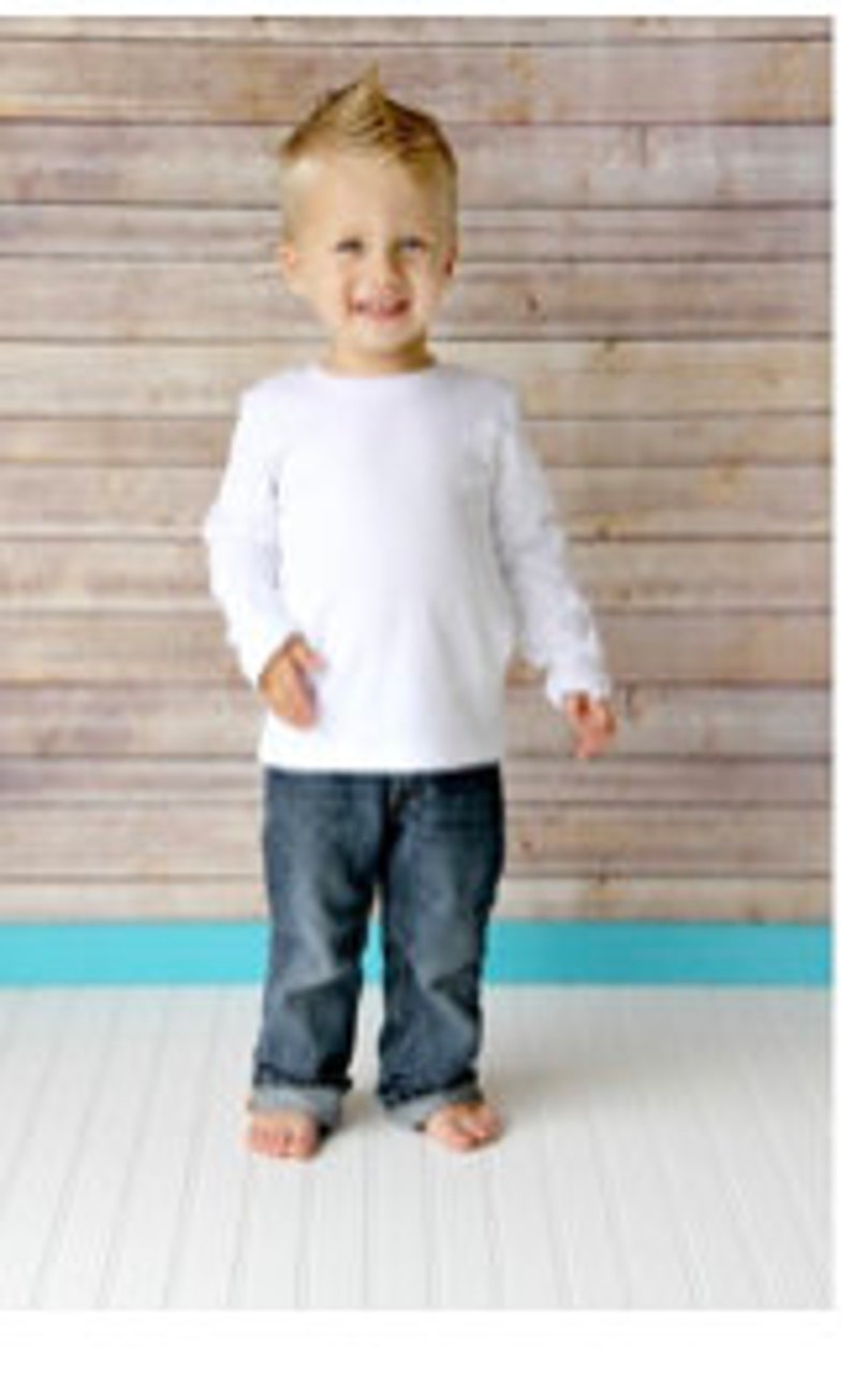May include: A white long-sleeved t-shirt on a young boy. The shirt has a crew neck and is made of a soft, comfortable fabric.