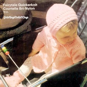 May include: A pink knitted baby outfit with a matching hat. The outfit is made of a soft, lightweight yarn and features a delicate lace pattern. The baby is sitting in a stroller. The pattern number is 2429.