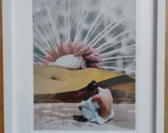 Puede incluir: Una impresión artística enmarcada que presenta a una persona sentada de espaldas al espectador, envuelta en tela blanca. El fondo incluye una gran flor rosa y blanca y formas abstractas similares a un desierto. El marco es blanco.