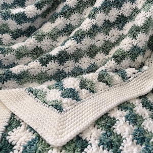 May include: A crocheted blanket with a white and green checkered pattern. The blanket is made with a soft, textured yarn and has a delicate, lacy look.