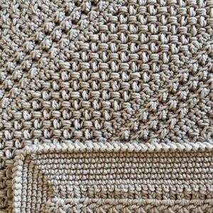 May include: Close-up of a beige crocheted blanket with a textured pattern. The blanket is made with a single crochet stitch and has a smooth, soft texture.