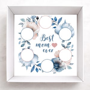 May include: A white box with a floral design and the text "Best mom ever." The design features blue and pink flowers with circular spaces for photos. The box is ideal for a Mother's Day gift.