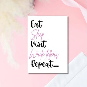 May include: A white card with the words "Eat Sleep Visit Write letters Repeat..." in black and pink script. The card is on a pink surface with a white envelope in the corner.