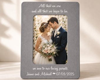 May include: A gray rectangular photo frame with rounded corners. The frame holds a wedding photo of a couple. Text on the frame reads "All that we are and all that we hope to be, we owe to our loving parents. Jaime and Michael 07/03/2025."
