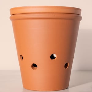 Könnte beinhalten: Terrakotta-Topf mit Abzugslöchern. Der Topf hat einen Deckel und ist hellbraun.