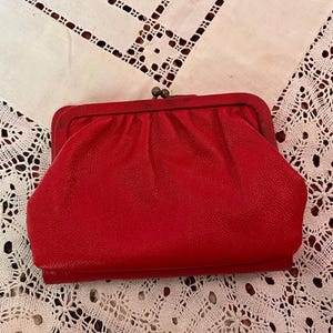 May include: A red leather clutch purse with a metal clasp.