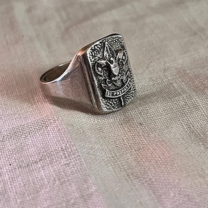 Puede incluir: Un anillo de plata con una cara rectangular que presenta el logotipo de los Boy Scouts of America y las palabras "Be Prepared".