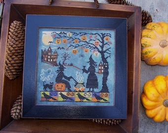 May include: A framed cross-stitch embroidery depicting a Halloween scene with two witches, a black cat, a cauldron, and a haunted house. The background is a blue sky with a full moon and jack-o'-lanterns.