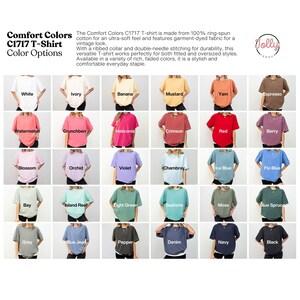 May include: A display of Comfort Colors C1717 T-shirts in various colors, including white, ivory, and black. The image showcases the color options available, with each shirt labeled with its respective name. The text describes the shirts as made of ring-spun cotton.