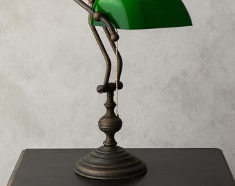 May include: A green-shaded banker's lamp with a bronze-colored base and arm, resting on a black table. The lamp features a curved arm and a pull chain. The green glass shade is a distinctive feature of this classic desk lamp.
