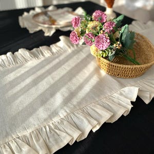 Soft ruffled table runner in white linen, styled for spring table decor and cozy gatherings. This French table runner complements french tablecloth and boho table runner themes. Ideal as a christmas runner, halloween tablecloth, or everyday white runner. A charming french tablecloth look, perfect for French table runner lovers and unique ruffled runner designs.