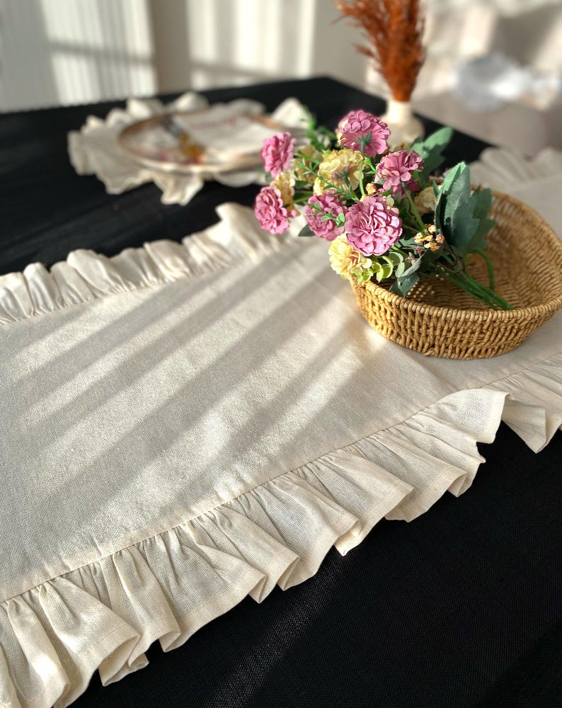 Soft ruffled table runner in white linen, styled for spring table decor and cozy gatherings. This French table runner complements french tablecloth and boho table runner themes. Ideal as a christmas runner, halloween tablecloth, or everyday white runner. A charming french tablecloth look, perfect for French table runner lovers and unique ruffled runner designs.