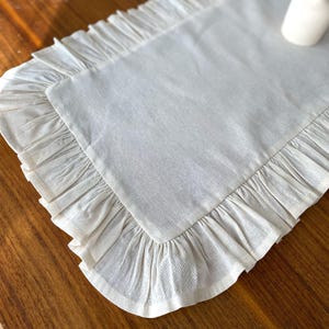 Soft ruffled table runner in white linen, styled for spring table decor and cozy gatherings. This French table runner complements french tablecloth and boho table runner themes. Ideal as a christmas runner, halloween tablecloth, or everyday white runner. A charming french tablecloth look, perfect for French table runner lovers and unique ruffled runner designs.