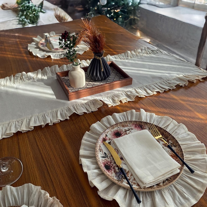 Soft ruffled table runner in white linen, styled for spring table decor and cozy gatherings. This French table runner complements french tablecloth and boho table runner themes. Ideal as a christmas runner, halloween tablecloth, or everyday white runner. A charming french tablecloth look, perfect for French table runner lovers and unique ruffled runner designs.