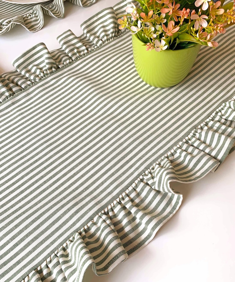 Green striped table runner with ruffled edges displayed on dining table, perfect for spring entertaining and farmhouse style decor.