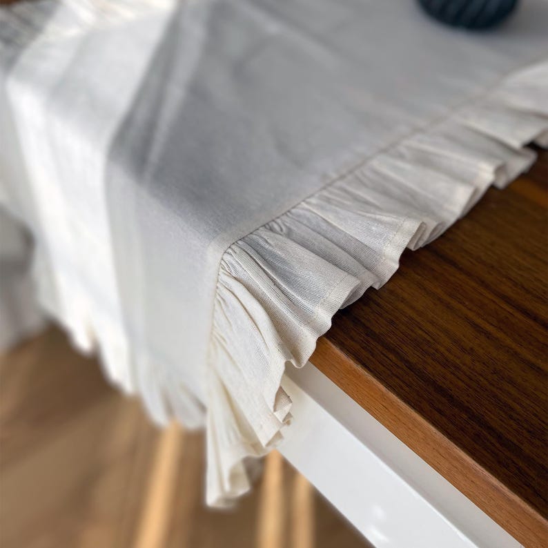 Soft ruffled table runner in white linen, styled for spring table decor and cozy gatherings. This French table runner complements french tablecloth and boho table runner themes. Ideal as a christmas runner, halloween tablecloth, or everyday white runner. A charming french tablecloth look, perfect for French table runner lovers and unique ruffled runner designs.