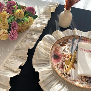 Soft ruffled table runner in white linen, styled for spring table decor and cozy gatherings. This French table runner complements french tablecloth and boho table runner themes. Ideal as a christmas runner, halloween tablecloth, or everyday white runner. A charming french tablecloth look, perfect for French table runner lovers and unique ruffled runner designs.