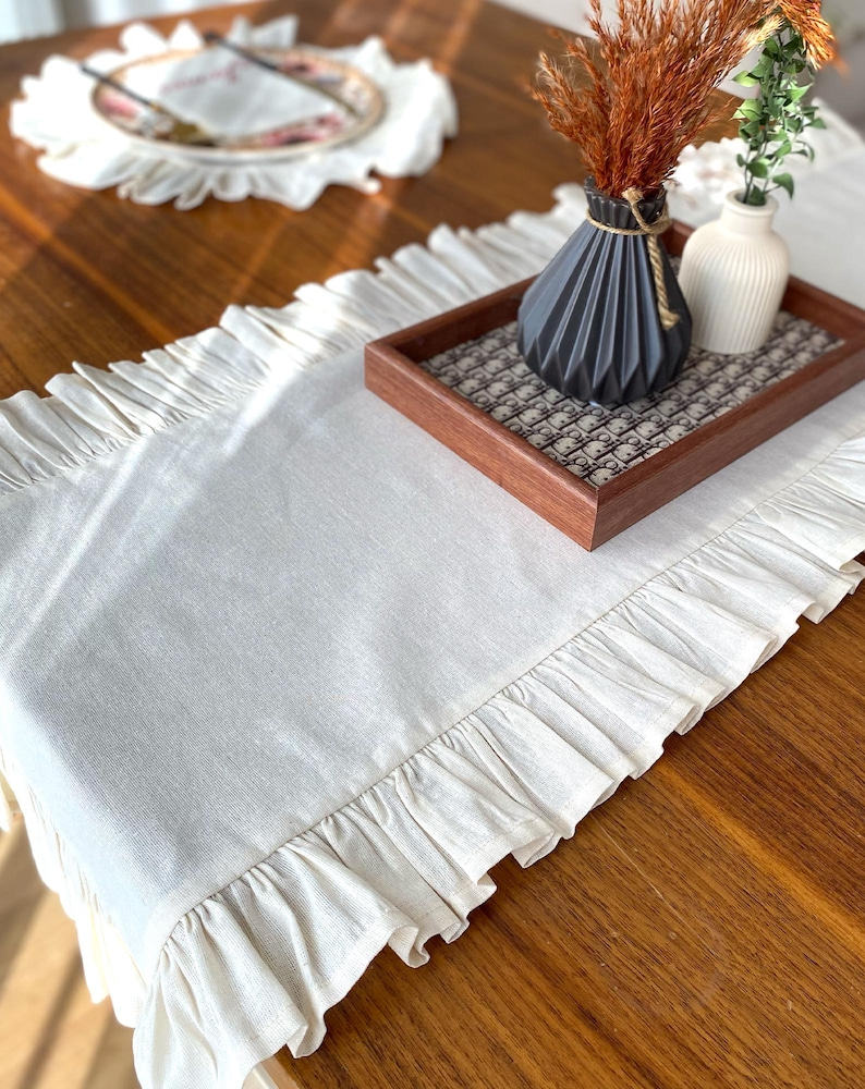 Soft ruffled table runner in white linen, styled for spring table decor and cozy gatherings. This French table runner complements french tablecloth and boho table runner themes. Ideal as a christmas runner, halloween tablecloth, or everyday white runner. A charming french tablecloth look, perfect for French table runner lovers and unique ruffled runner designs.