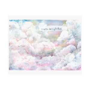 May include: A watercolor painting of a sky filled with fluffy clouds in shades of pink, blue, and white. The text "You're delightful" is written in black on a white rectangle in the center of the image.