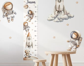May include: A wall decal set featuring a vertical growth chart with the name Jason, marked with numbers 50 to 150. The design includes watercolor-style illustrations of astronauts, a rocket ship launching into clouds, a robot, and stars.