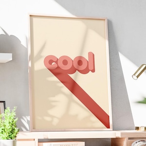 May include: A wooden desk with a framed print that says "cool" in red letters. A small desk lamp, a framed picture, and a small plant are on the desk. A wooden chair is in front of the desk.