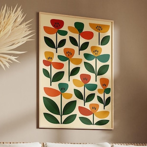 May include: A framed floral art print with a cream background, featuring stylized flowers in red, orange, yellow, and teal. The artwork hangs above a cream-colored sofa with decorative pillows and a blanket. Dried plants and wooden geometric shapes complete the room.