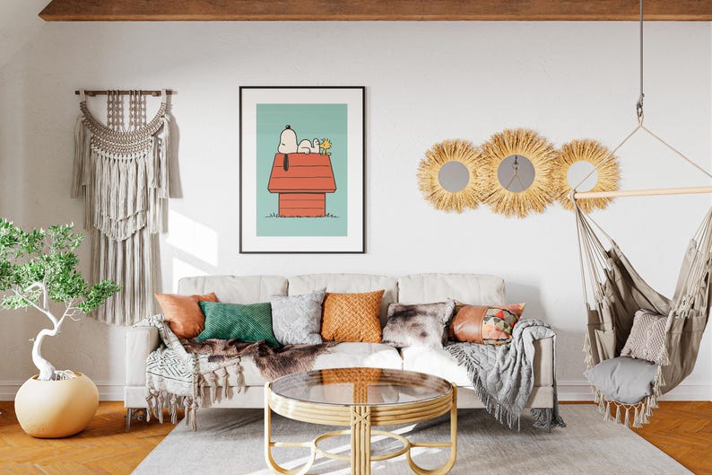 May include: A living room with a beige sofa, cushions, and a framed Snoopy print. A round coffee table, macrame wall hanging, and a hanging chair are visible. The room has a neutral colour palette with wooden accents and a rug. The room is well lit.