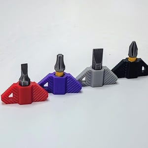 May include: Four multi-colored screwdriver bit holders. The holders are red, purple, gray, and black. Each holder has a unique design with a yellow base and a silver bit. The items are on a white background.