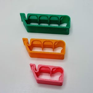 May include: Three plastic cable organizers in different colors: green, orange, and pink. Each organizer has four slots for holding cables.