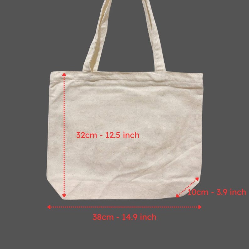 May include: A cream-colored tote bag with two handles. The bag is rectangular, with measurements of 12.5 inches in height, 14.9 inches in width, and 3.9 inches in depth. The bag is made of a plain, woven fabric.
