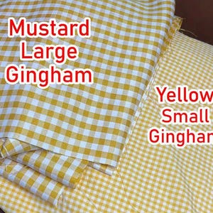 May include: Two pieces of fabric featuring a gingham pattern. The left piece is mustard yellow and white with a large check pattern, labeled 'Mustard Large Gingham'. The right piece is yellow and white with a small check pattern, labeled 'Yellow Small Gingham'.