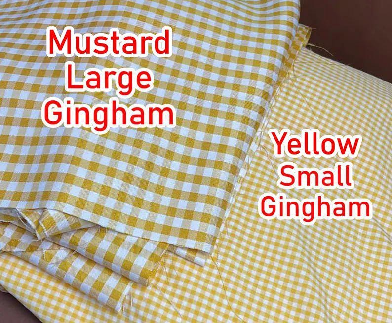 May include: Two pieces of fabric featuring a gingham pattern. The left piece is mustard yellow and white with a large check pattern, labeled 'Mustard Large Gingham'. The right piece is yellow and white with a small check pattern, labeled 'Yellow Small Gingham'.